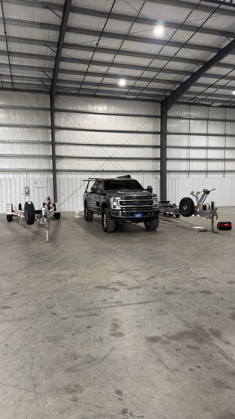 Waypoint 239 truck parked between two boat trailers in a storage warehouse