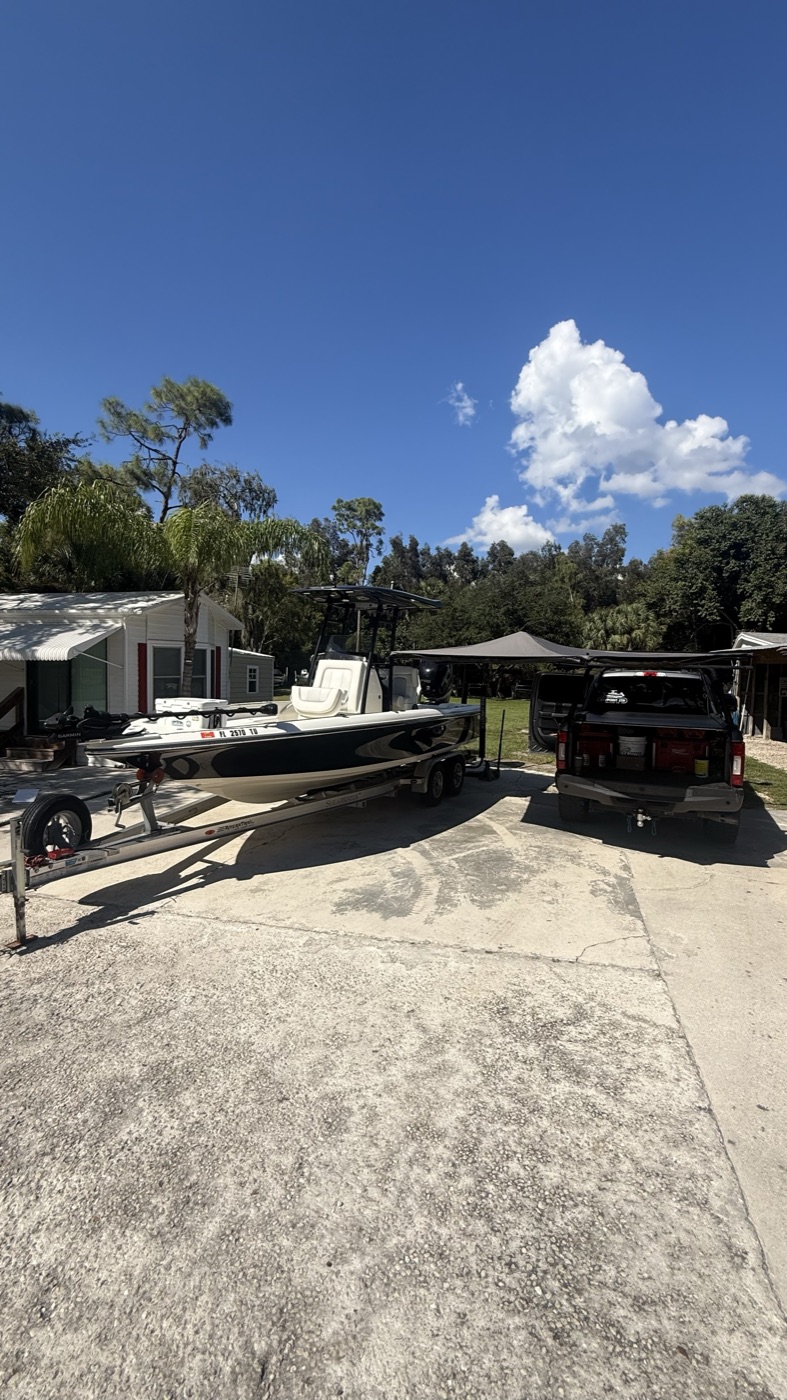 Bay boat on a tandem-axle trailer next to the Waypoint 239 truck in a driveway
